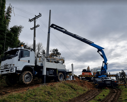 A digger holding a new power pole.